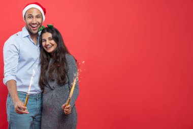 Mutlu çift Noel partisini birlikte kutluyor gülümsüyor kırmızı arka planda izole edilmiş ışıl ışıl eğleniyor. Reklam için reklam alanı.