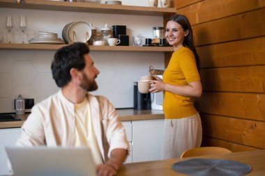 Evde sabahlar. Sabahları mutfakta bir çift, erkek çalışıyor, kadın çay yapıyor.