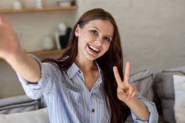 Gülümseyen kadın selfie çekiyor ve V işareti gösteriyor.