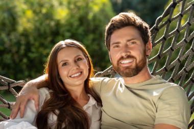 Uyum. Sevimli, gülümseyen bir çift parkta hamakta otururken eğleniyor.