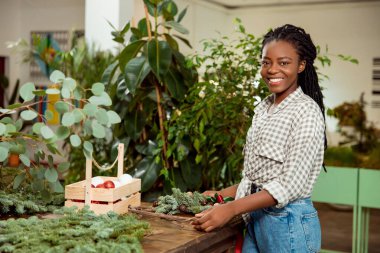 Çiçekçi. Çiçekçi dükkanındaki güzel Afrikalı Amerikalı genç kadın neşeli görünüyor.