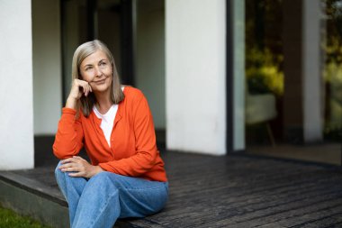 Güzel bir kadın. Üst düzey güzel kadın evinin merdivenlerinde oturuyor ve kendini mutlu hissediyor.