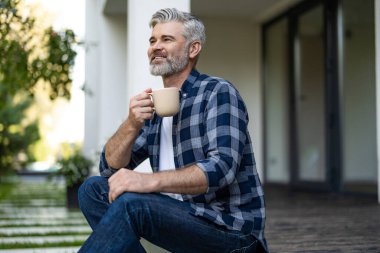 Sabah kahvesi. Elinde bir fincan kahveyle kıdemli, sakallı bir adam.