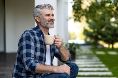 Sabah kahvesi. Elinde bir fincan kahveyle kıdemli, sakallı bir adam.