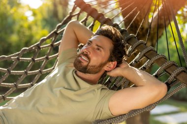 Rahatlama. Sakallı genç adam bir hamakta yatıyor ve rahatlamış hissediyor.