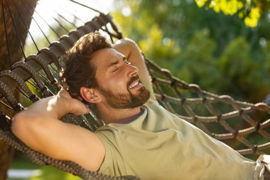 Rahatlama. Sakallı genç adam bir hamakta yatıyor ve rahatlamış hissediyor.