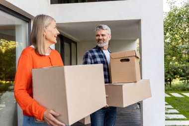 Neşeli kıdemli adam ve kadın taşınma sırasında evde kutu taşıyarak birlikte çalışıyorlar.