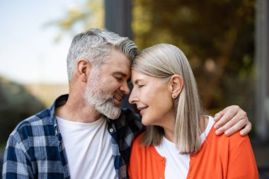 Şefkatle sarılın. Gri saçlı sakallı adam kadına nazikçe sarılıyor ve ikisi de rahatlamış hissediyor.