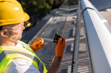 Profesyonel işçi dışarıda güneş enerjisi toplayıcılarını tamir edip kontrol ediyor.