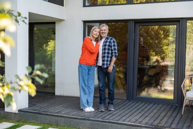 Evin girişinde. Evin girişinde iki kişi var ve memnun görünüyorlar.