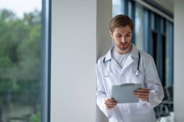 İçerde duran genç doktor panoya not alıyor.