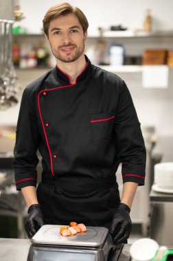 Erkek aşçı profesyonel mutfakta sağlıklı yemek için taze balık ölçüyor.