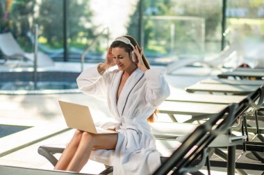 İletişim. Kulaklıklı bir kadın spa merkezinde oturuyor ve video görüşmesi yapıyor.