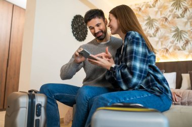 Otele varış. Geldikten sonra bir otel odasındaki yatakta oturan çift.