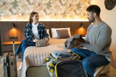 Eşyalarımı yerleştiriyorum. Genç çift tatil için otele vardıktan sonra bavullarını boşaltıyor.