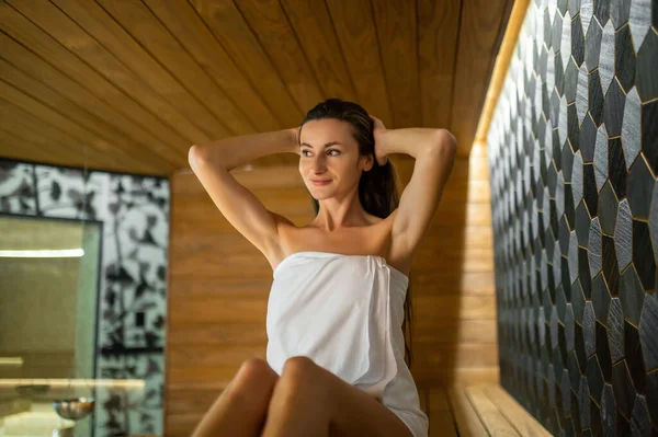 Sauna zevki. Saunada bir bankta oturan hoş beyaz bir kadın.