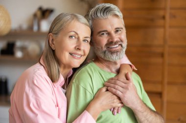 Keyifli olgun çift rahat oturma odasında poz veriyor.