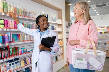 İlaçlardan bahsediyorum. Kadın müşteri eczane asistanıyla konuşuyor ve ikisi de işin içinde gibi görünüyor.