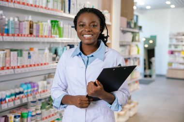 Eczacı iş başında. Eczanede gülümseyen esmer bir kadın eczacı.