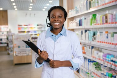 Eczacı iş başında. Eczanede gülümseyen esmer bir kadın eczacı.