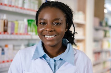 Eczacı iş başında. Eczanede gülümseyen esmer bir kadın eczacı.