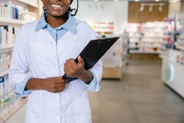 Eczacı iş başında. Eczanede gülümseyen esmer bir kadın eczacı.