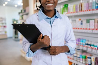 Eczanede. Eczanede laboratuvar önlüklü Afrikalı Amerikalı genç bir kadın.