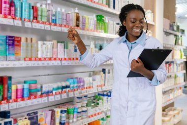 Eczanede. Eczanede laboratuvar önlüklü Afrikalı Amerikalı genç bir kadın.