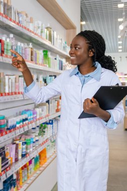 Eczanede. Eczanede laboratuvar önlüklü Afrikalı Amerikalı genç bir kadın.
