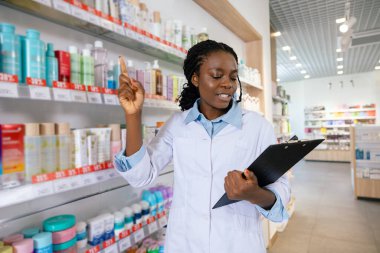 Eczacı iş başında. Genç gülümseyen eczacı eczanede envanter yapıyor.