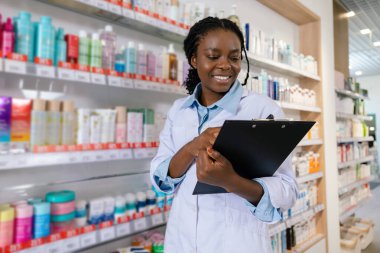 Eczacı iş başında. Genç gülümseyen eczacı eczanede envanter yapıyor.