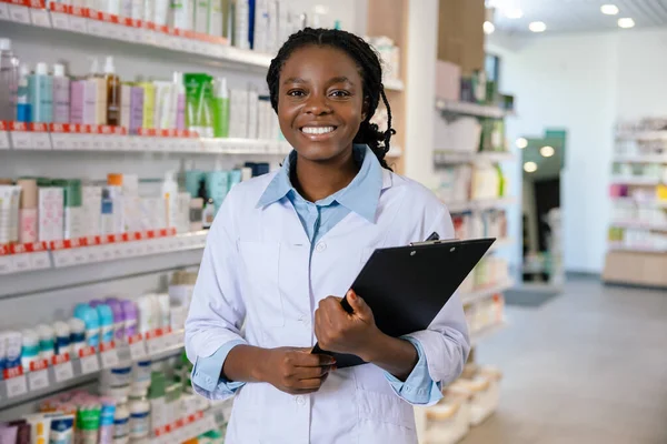 Eczacı iş başında. Eczanede gülümseyen esmer bir kadın eczacı.