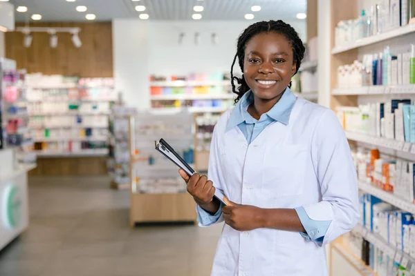 Eczacı iş başında. Eczanede gülümseyen esmer bir kadın eczacı.