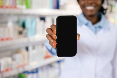 Telefonlu bir kadın. Elinde telefon tutan laboratuvar önlüklü Afrikalı Amerikalı genç bir kadın.