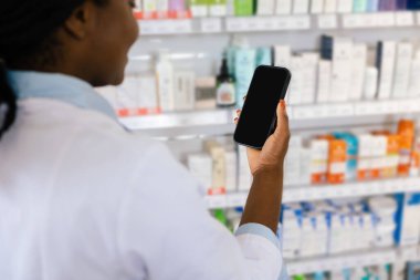 Telefonlu bir kadın. Elinde telefon tutan laboratuvar önlüklü Afrikalı Amerikalı genç bir kadın.