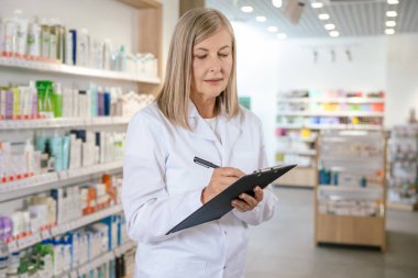 Eczacı iş başında. Kadın eczacı notlar alıyor ve olaya dahil oluyor.