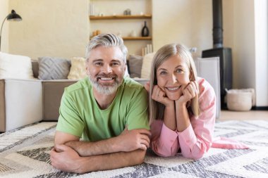 Gülümseyen son sınıf çifti rahat oturma odasında yerde dinleniyor.