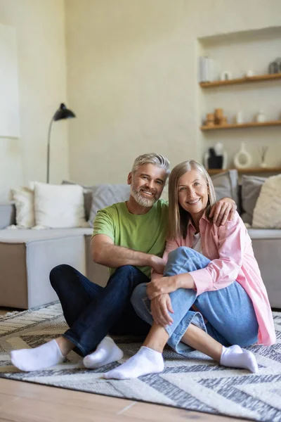 Gülümseyen yaşlı çift evde rahat bir ortamda yerde dinleniyor.