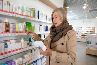 İlaç seçiyorum. Kafkasyalı hasta, yetişkin bir kadın eczaneden hap seçiyor.