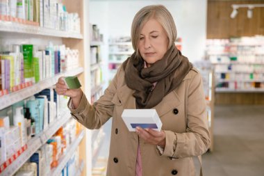 İlaç seçiyorum. Kafkasyalı hasta, yetişkin bir kadın eczaneden hap seçiyor.