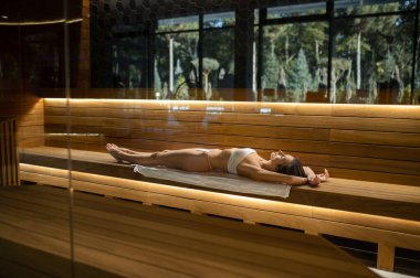 Spa mı? Sıska bir kadın spa salonundaki bankta uzanıyor ve prosedürlerin tadını çıkarıyor.