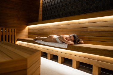 Spa mı? Sıska bir kadın spa salonundaki bankta uzanıyor ve prosedürlerin tadını çıkarıyor.