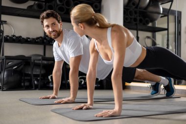 Antrenman yapıyorum. Spor salonunda antrenman yapan ve tahta üzerinde duran iki kişi.