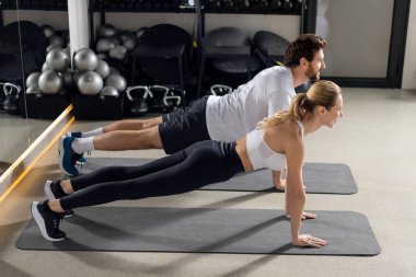 Antrenman yapıyorum. Spor salonunda antrenman yapan ve tahta üzerinde duran iki kişi.