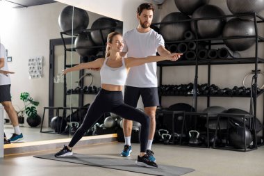 Koçla antrenman. Spor salonunda koçla çalışan sarışın bir kadın. Yoğunlaşmış görünüyor.