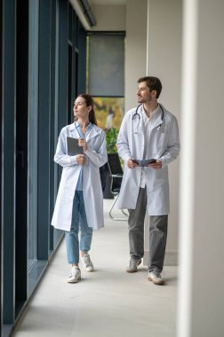 Tıbbi tartışma. Doktorlar klinik koridorunda yürüyor ve soruşturma sonuçlarını tartışıyorlar.