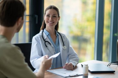 Reçeteli. Laboratuvar önlüklü kadın doktor hastaya reçete yazıyor.