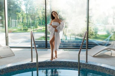 Rahatlamış hissediyorum. Beyaz bornozlu hoş genç bir kadın vaktini kaplıca merkezinde geçiriyor.