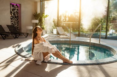 Rahatlamış hissediyorum. Beyaz bornozlu hoş genç bir kadın vaktini kaplıca merkezinde geçiriyor.