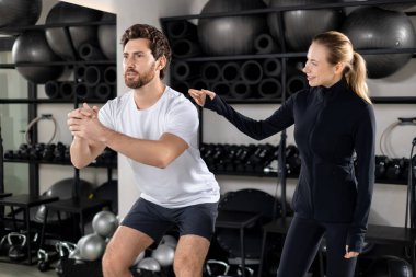 Antrenman arası. Sarışın genç bayan koç, antrenman sırasında genç bir adamı çalıştırıyor.